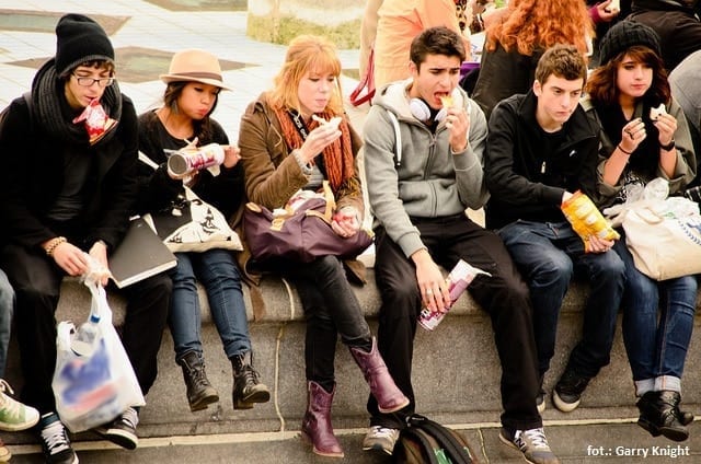Grupa nastolatków - siedzą na murku i jedzą
